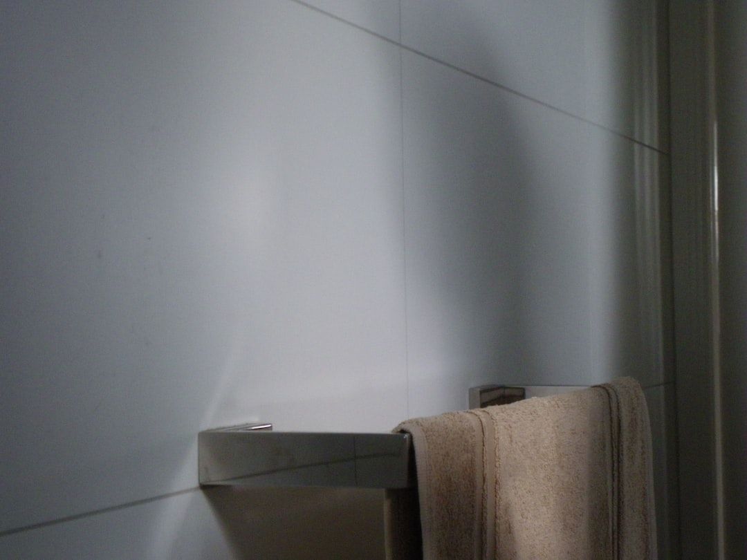 En moderne håndkleholder i krom med et lyst håndkle på et flislagt bad.
